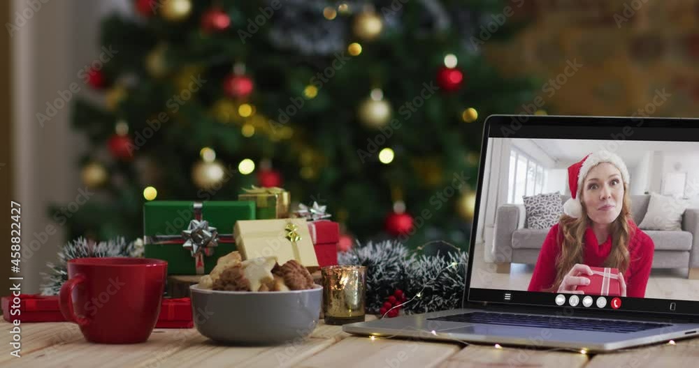 Happy caucasian woman on video call on laptop, with christmas decorations and tree Happy caucasian woman on video call on laptop, with christmas decorations and tree