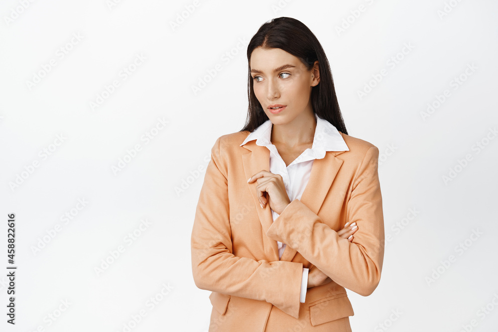 Successful beautiful corporate woman looking aside, standing in stylish suit against white background Successful beautiful corporate woman looking aside, standing in stylish suit against white background