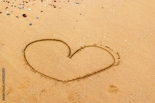 The heart symbol on the beach is drawn on the yellow sands of the shore. Valentine's Day.