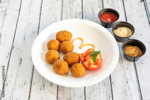 serving of round chicken croquettes with tomato and tomato sauces, mayonnaise and dijon mustard to dip