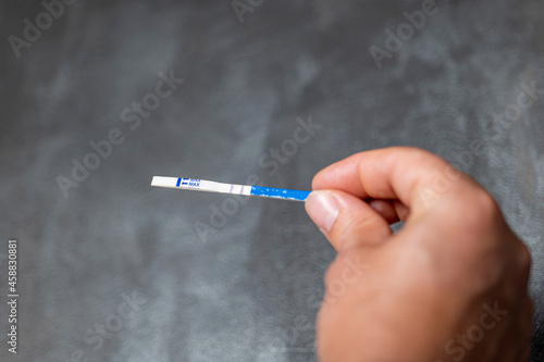 girl holding a positive pregnancy test in her hands on a gray background