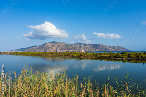 Salina island (Aeolian archipelago), Messina, Sicily, Italy, 08.16.2021: view of the salt lake in Punta Lingua with  Lipari island in the background. © Giongi63