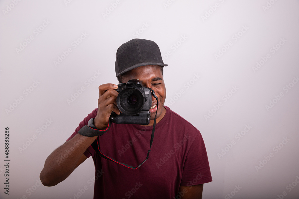 Photographer takes a picture while looking through the camera viewfinder. African photographer isolated on white background. Photograph taken in the studio. Professional Photographer concept. Photographer takes a picture while looking through the camera viewfinder. African photographer isolated on white background. Photograph taken in the studio. Professional Photographer concept.