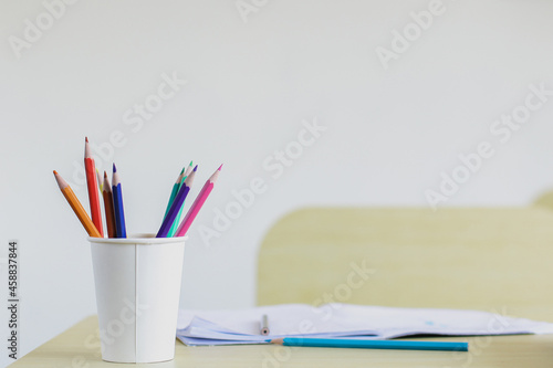 Close up of colored pencils in a Styrofoam cup on wooden desk