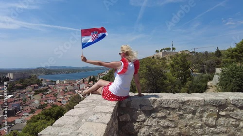 Woman on the walls of Barone Fortress with Croatian flag on Sibenik cityscape. View of St. Michael castle and St. John's Fort. Sibenik historic city of Croatia in Dalmatia. photo