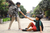 A student boy helps to pull his friend to his feet