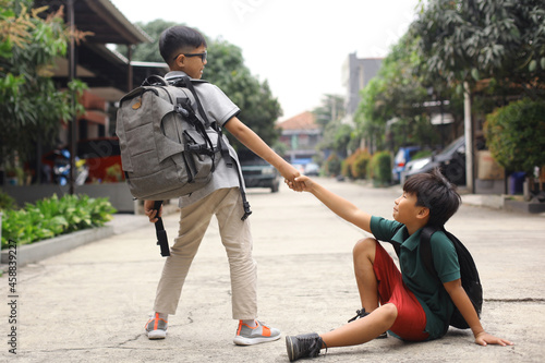 A student helps to pull his fallen friend to his feet © Gatot