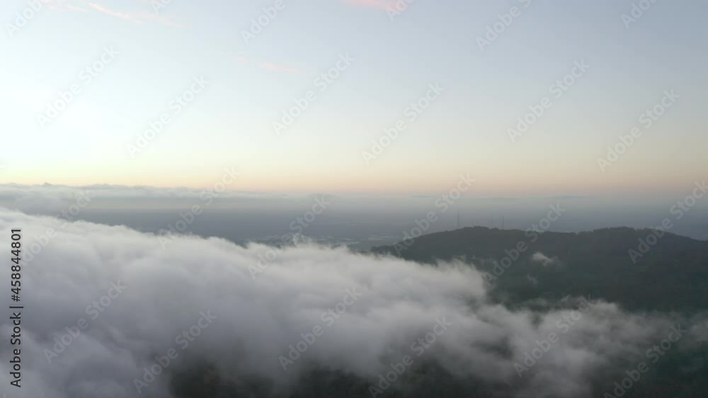Drone ascent and looking left over low cloud and tv communication towers during dusk. Drone ascent and looking left over low cloud and tv communication towers during dusk.