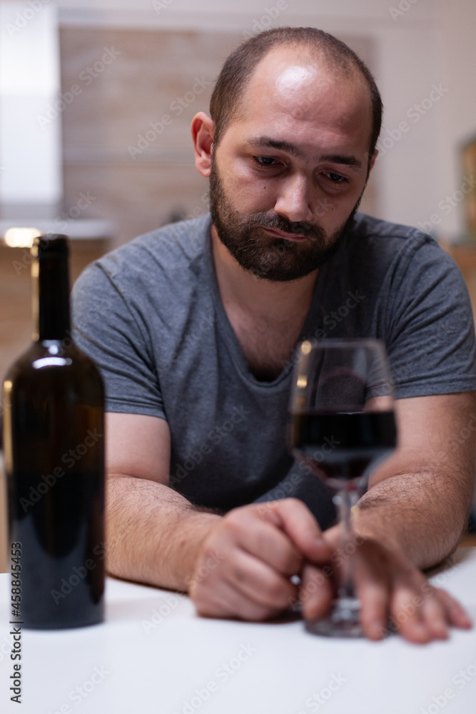 Close up of bottle and glass of wine prepared for man feeling unhappy and lonely. Person drinking alcoholic beverage, booze, liquor while being alone in kitchen. Intoxicated adult Close up of bottle and glass of wine prepared for man feeling unhappy and lonely. Person drinking alcoholic beverage, booze, liquor while being alone in kitchen. Intoxicated adult