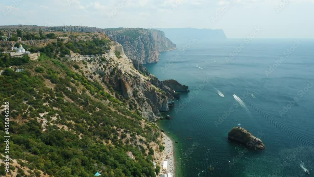 Aerial view of calm azure sea and volcanic rocky cliffs of Mys Fiolent. Pleasure trip boats moored in the bay. Nature summer ocean sea beach background. Holiday, vacation and travel concept Aerial view of calm azure sea and volcanic rocky cliffs of Mys Fiolent. Pleasure trip boats moored in the bay. Nature summer ocean sea beach background. Holiday, vacation and travel concept