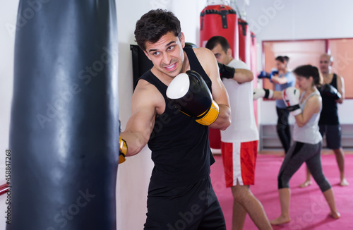 athletic works out blows on the punching bag in training © JackF