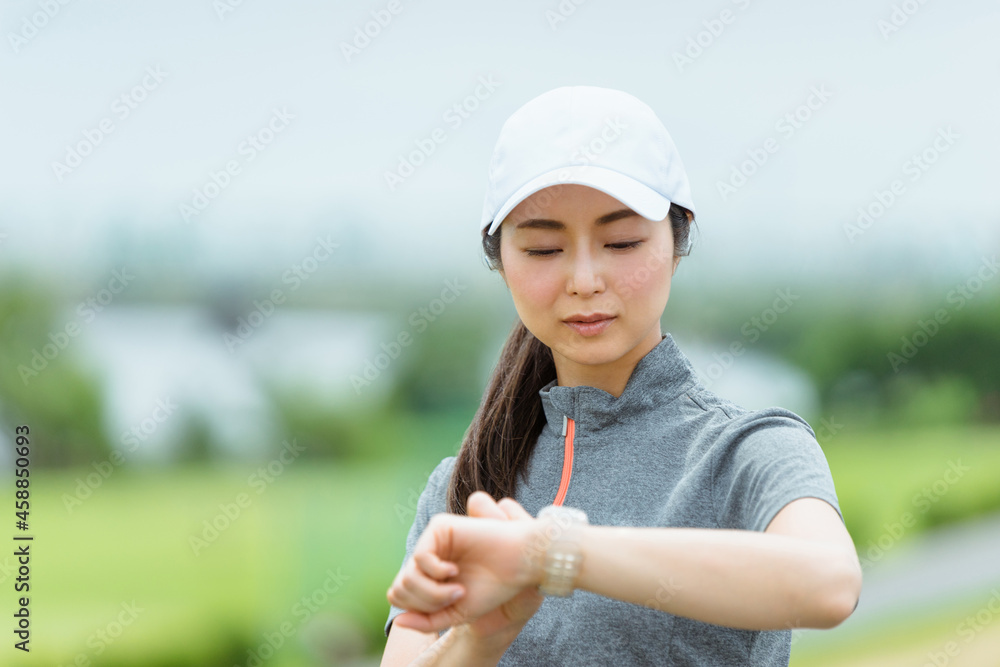 スマートウォッチを見てランニングをする女性 スマートウォッチを見てランニングをする女性