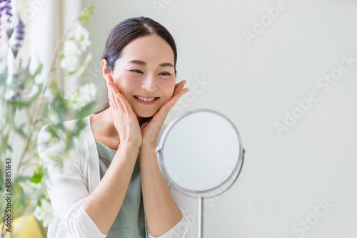 鏡を見てスキンケアをする女性（ビューティーイメージ）