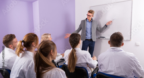 Confident male student answering near whiteboard in front group of students in auditorium