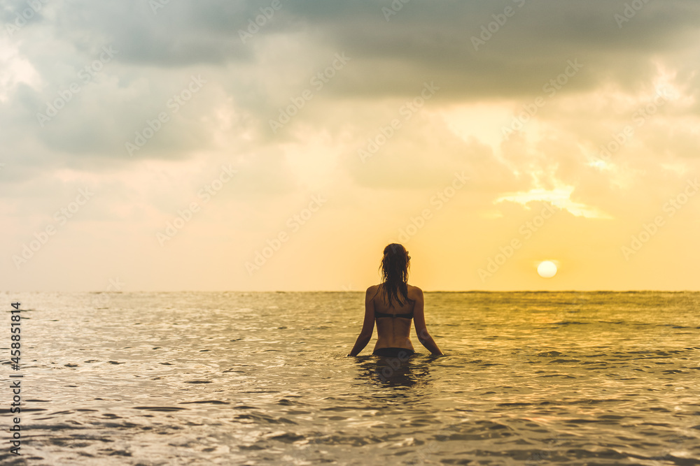 Woman's silhouette against calm sunset beach