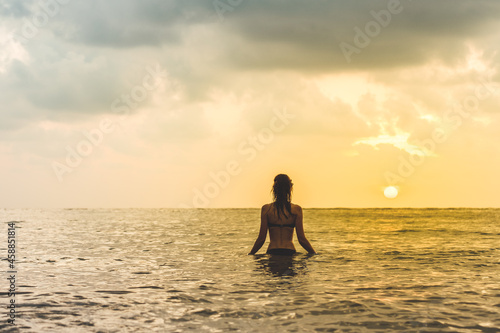 Woman's silhouette against calm sunset beach