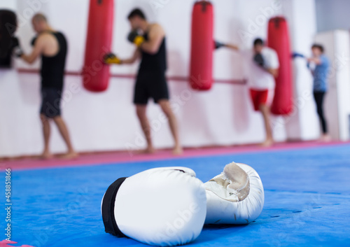 Athletes are beating a boxing bag on background.