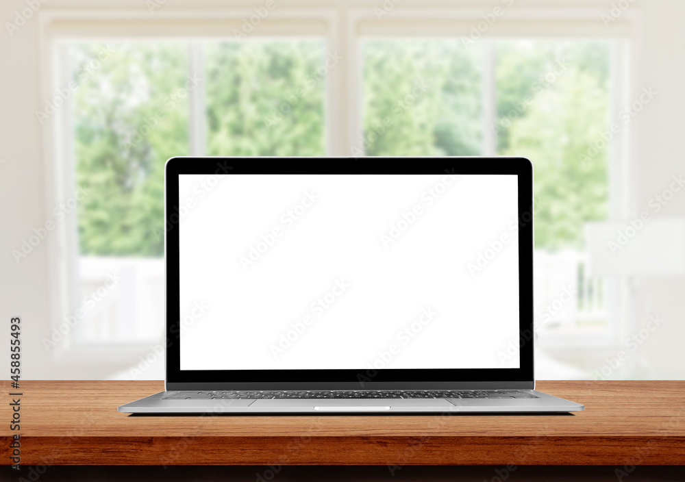Laptop with blank white screen on wooden table and blurry image of Living room in background. Laptop with blank white screen on wooden table and blurry image of Living room in background.