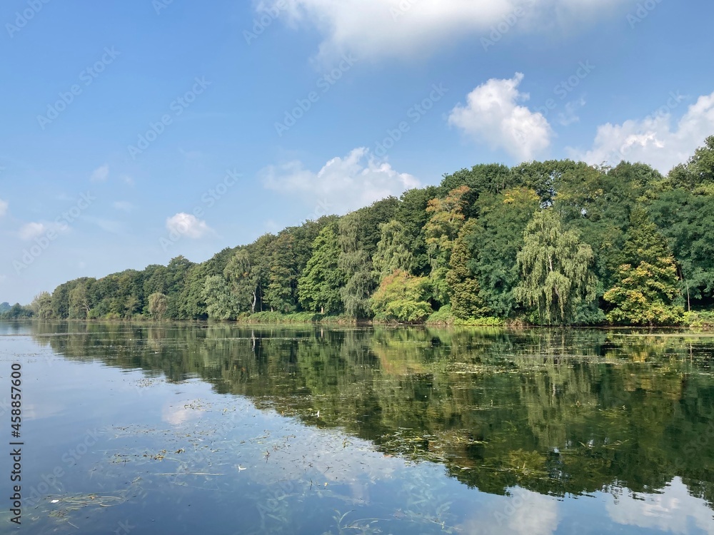 Landschaft am See mit Spiegelung der Bäume im Wasser