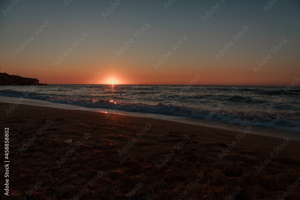 waves wash the rocky shore of the sea. Sunset. Reflection in the water of the bridge and rays waves wash the rocky shore of the sea. Sunset. Reflection in the water of the bridge and rays