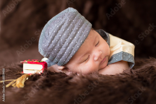 A cute Asian infant Muslim in thobe with prayer cap on bed in home, translation is noble quran photo