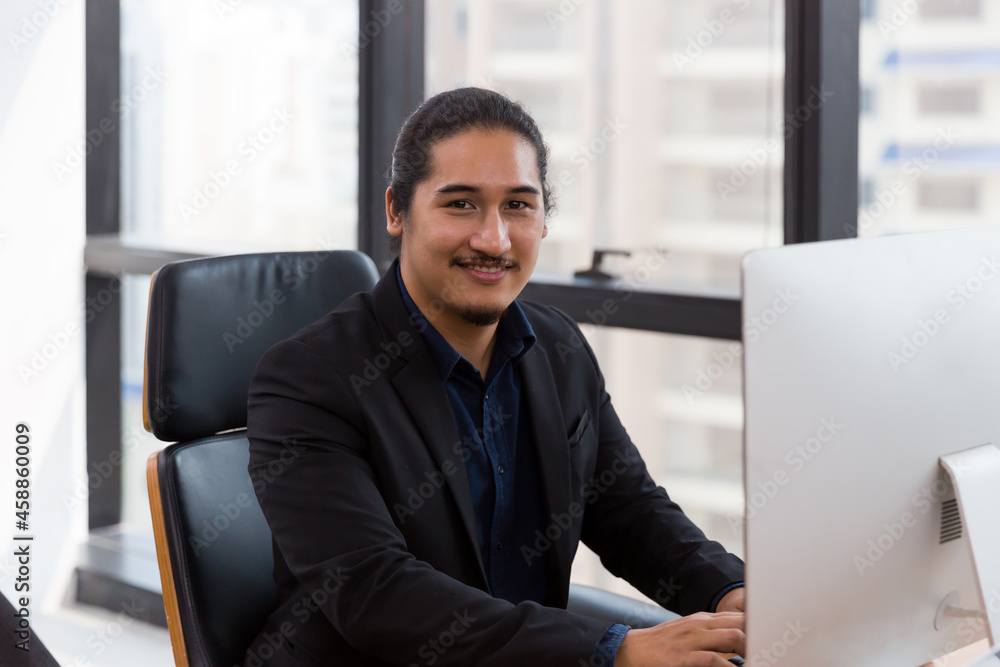 Asian business man working with computer desktop near window at work. Man using computer desktop near window in the office