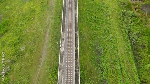 Reverse aerial footage of an elevated railroad, grassland both left and right, Saraburi, Thailand. photo