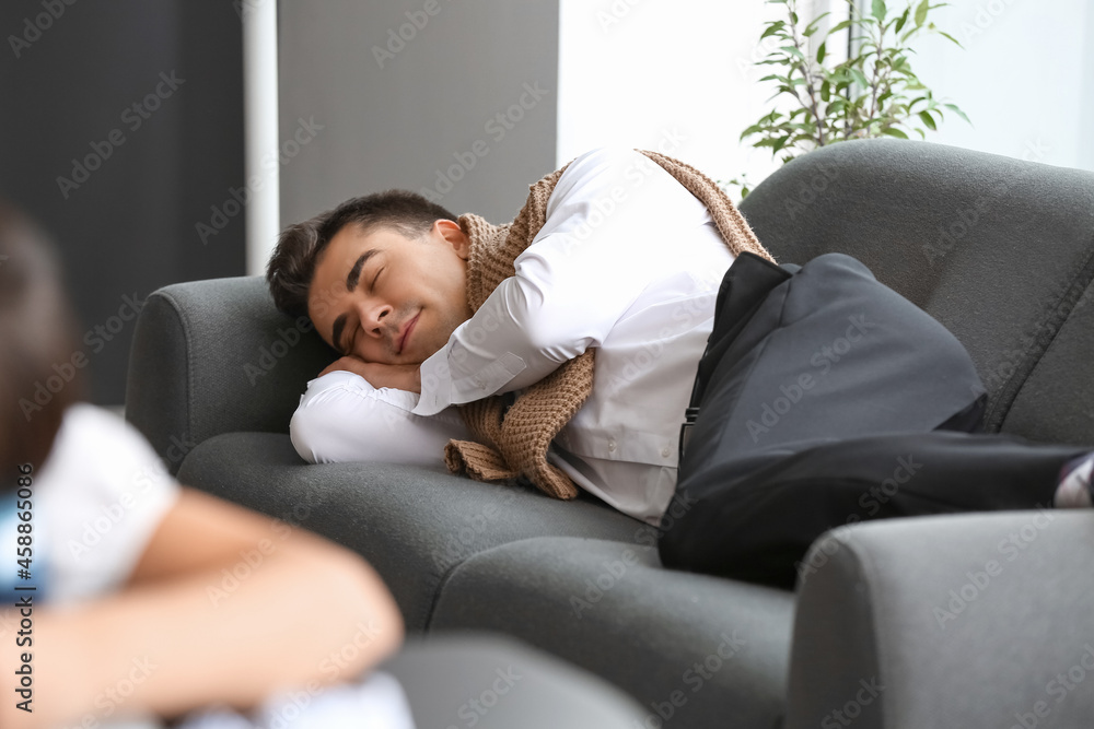 Young businessman sleeping on sofa in office