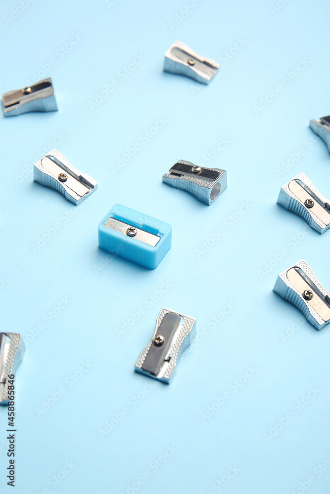 Fototapeta premium Blue sharpener among silver ones on color background. Concept of uniqueness