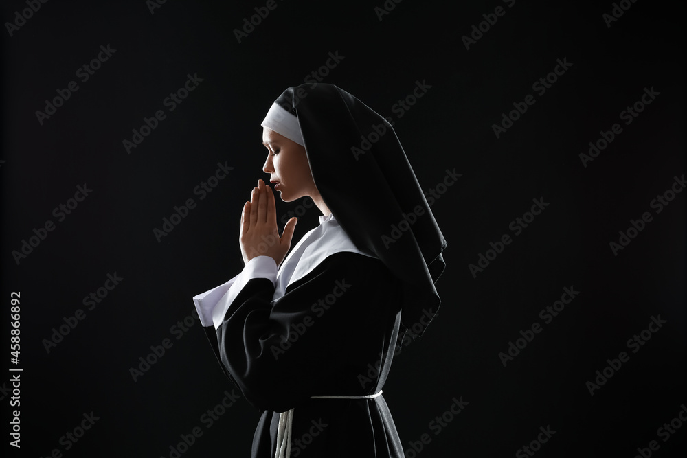 Young praying nun on dark background Young praying nun on dark background