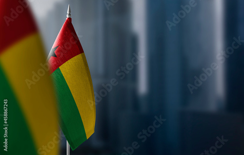 Small flags of Guinea Bissau on a blurry background of the city photo