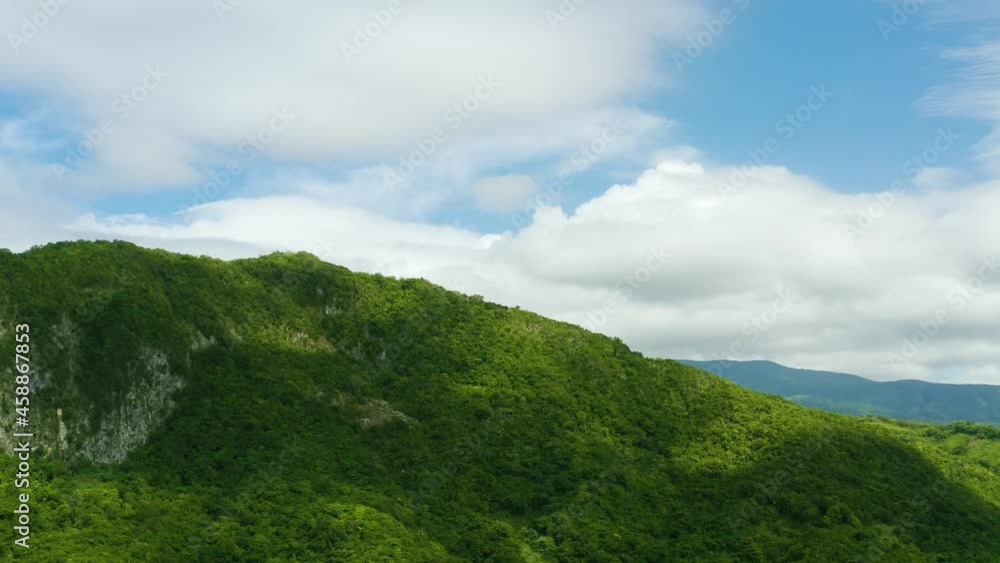 The green peak of the Barahona mountain range of the Dominican Republic. Green palm jungle in mountains Caribbean island landscape. Mountains and blue sky on a summer day.