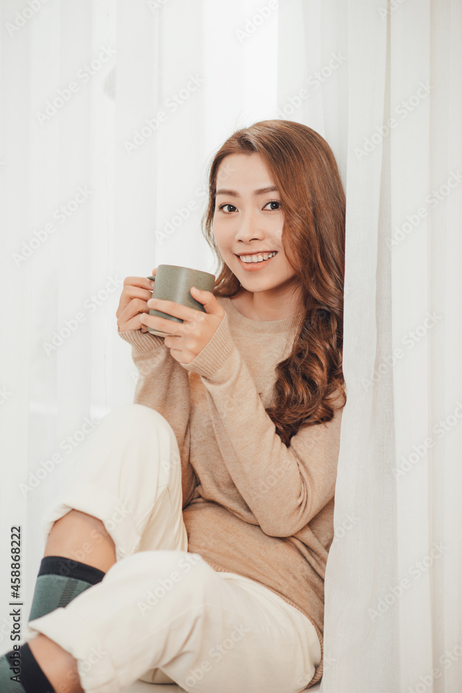 Young woman with cup of hot tea basking on xmas holidays.