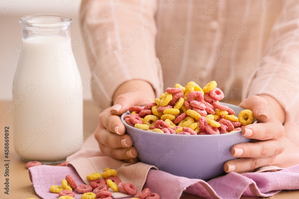 Woman holding bowl with different corn rings on table Woman holding bowl with different corn rings on table
