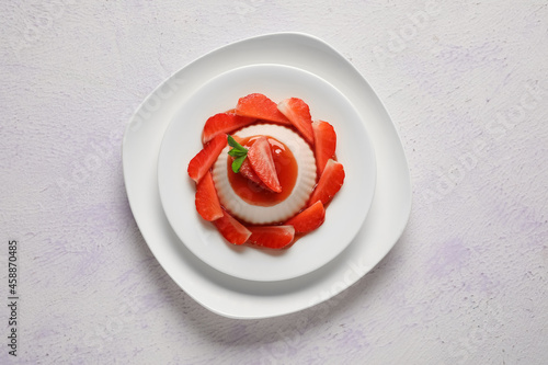 Plate with delicious strawberry panna cotta on light background