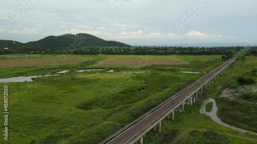 Angled aerial footage towards the horizon with hills trees, farmland, and the elevated railway, Muak Klek, Saraburi, Thailand. photo