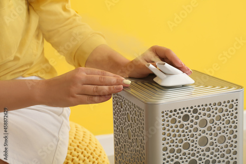 Woman with modern air humidifier in room