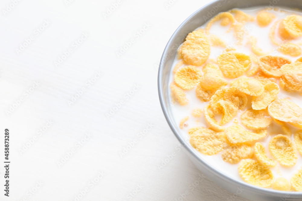 Bowl of tasty cornflakes with milk on light wooden background, closeup Bowl of tasty cornflakes with milk on light wooden background, closeup