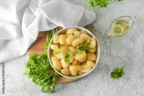 Bowl with tasty gnocchi on light background photo