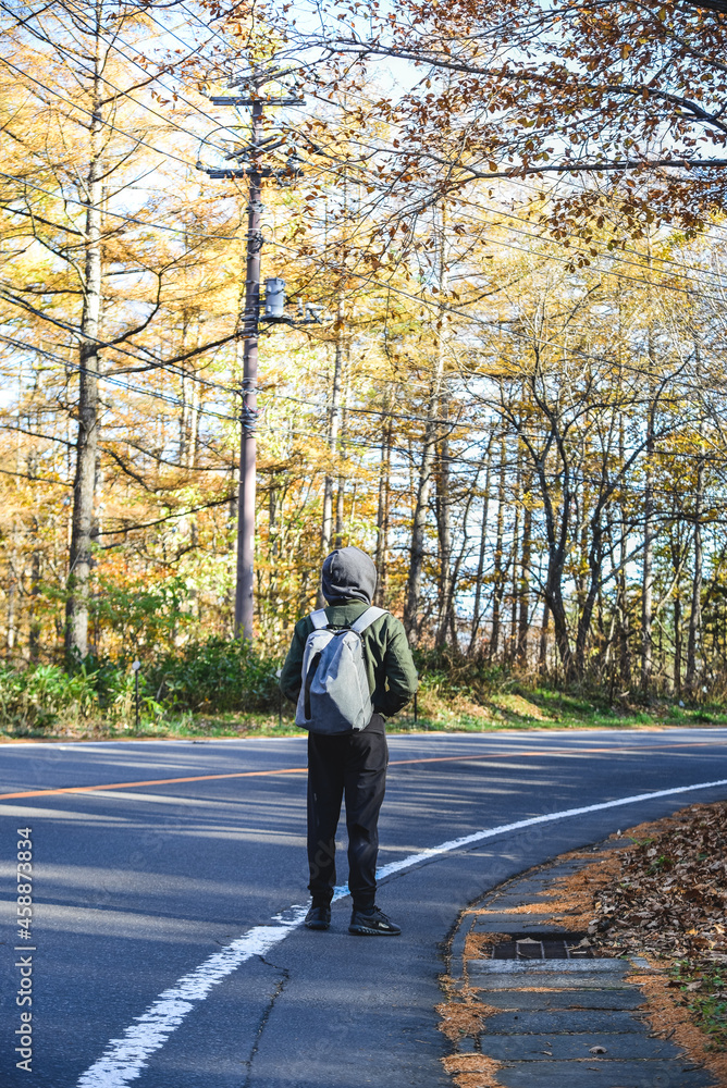 Young man walking on street of autumn forest