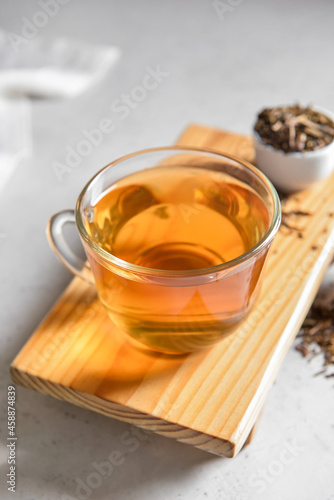 Wooden board with tasty hojicha green tea on light background