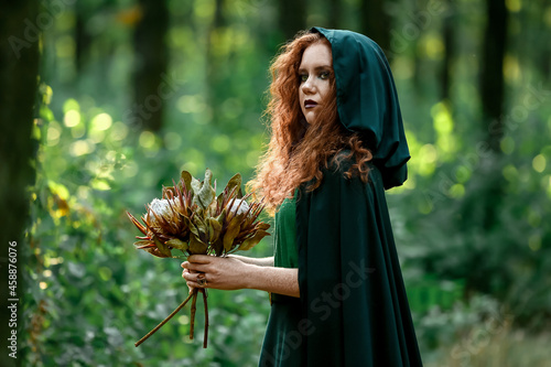 фотографія Young witch in green forest