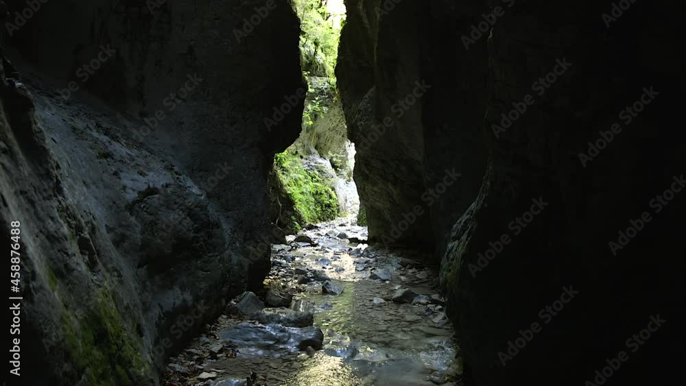 Lush green vegetation at the end of a deep narrow canyon with a stream ...
