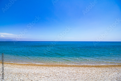 Fototapeta Naklejka Na Ścianę i Meble -  Pebbles on the beach and turquoise sea against clear blue sky. Summer background