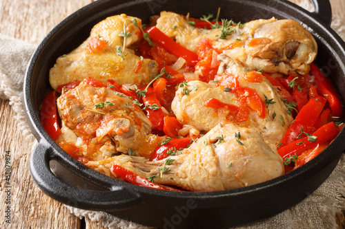 One pot Basque Chicken with Bell Peppers, herbs, tomatoes and onion close up in the pan on the table. Horizontal