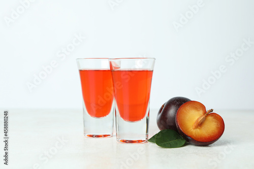 Plum brandy shots and ingredients on white textured table