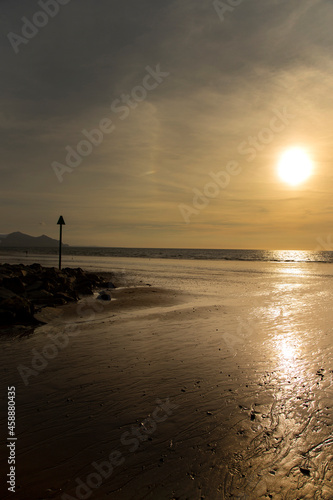 Dinas Dinlle beach with high tide markers at sunset.  Welsh coast beach holiday concept photo