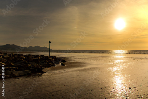 Dinas Dinlle beach with high tide markers at sunset.  Welsh coast beach holiday concept photo