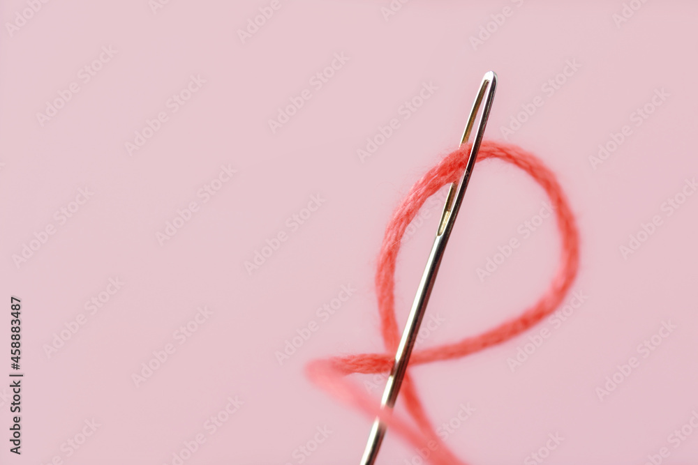 Fototapeta premium Close-up of sewing needle eye with pink thread