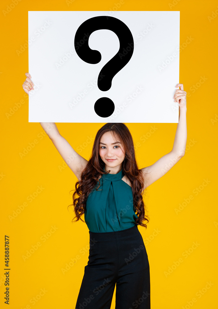 Young happy Asian women holding huge white cardboard sign with question mark. Standing isolated on bright yellow background Young happy Asian women holding huge white cardboard sign with question mark. Standing isolated on bright yellow background